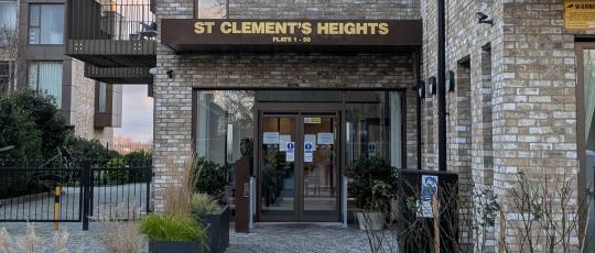 Image of path leading to Heights building entrance with glass door and name above