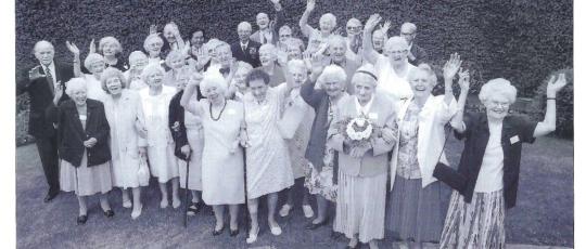 Black and white image of a group of residents smiling with arms in the air