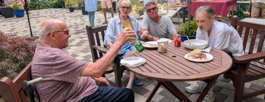People sitting with drinks around a table in the courtyard at the Heights BBQ